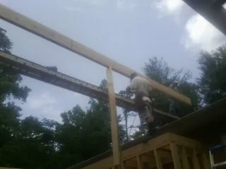 Carpenter setting a ridge beam over a new addition frame — Ice Dam Removal by Roofing Brothers in Mannsville