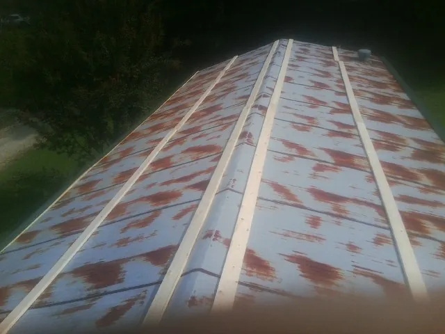 Rusted metal roof panels with new wood purlins before replacement — Storm Damage Roof Repair in Mannsville by Roofing Brothers