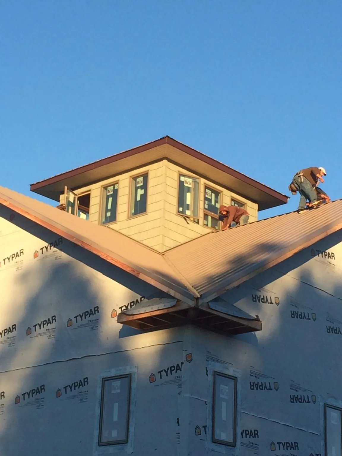 Roofers working around a rooftop cupola on a new metal roof at sunset — Roof Waterproofing in Mannsville by Roofing Brothers